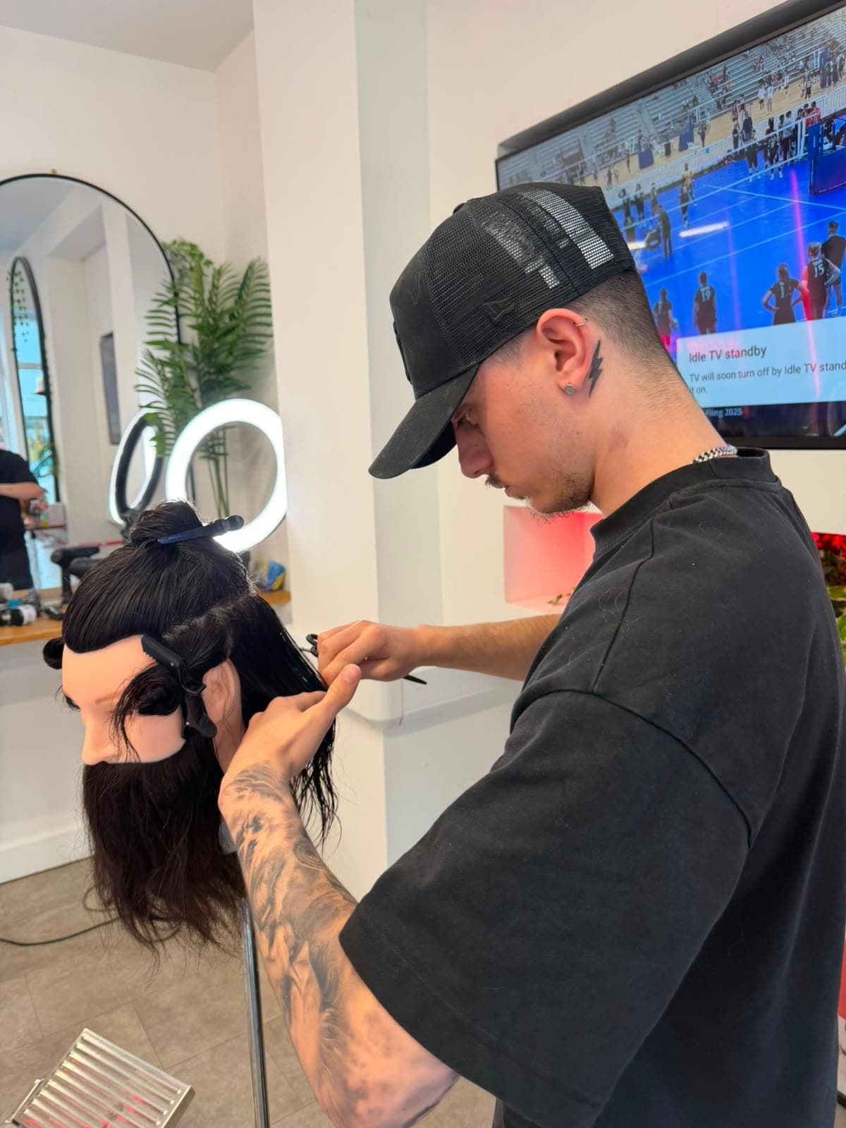 Barber practising a scissor cut on a training mannequin head